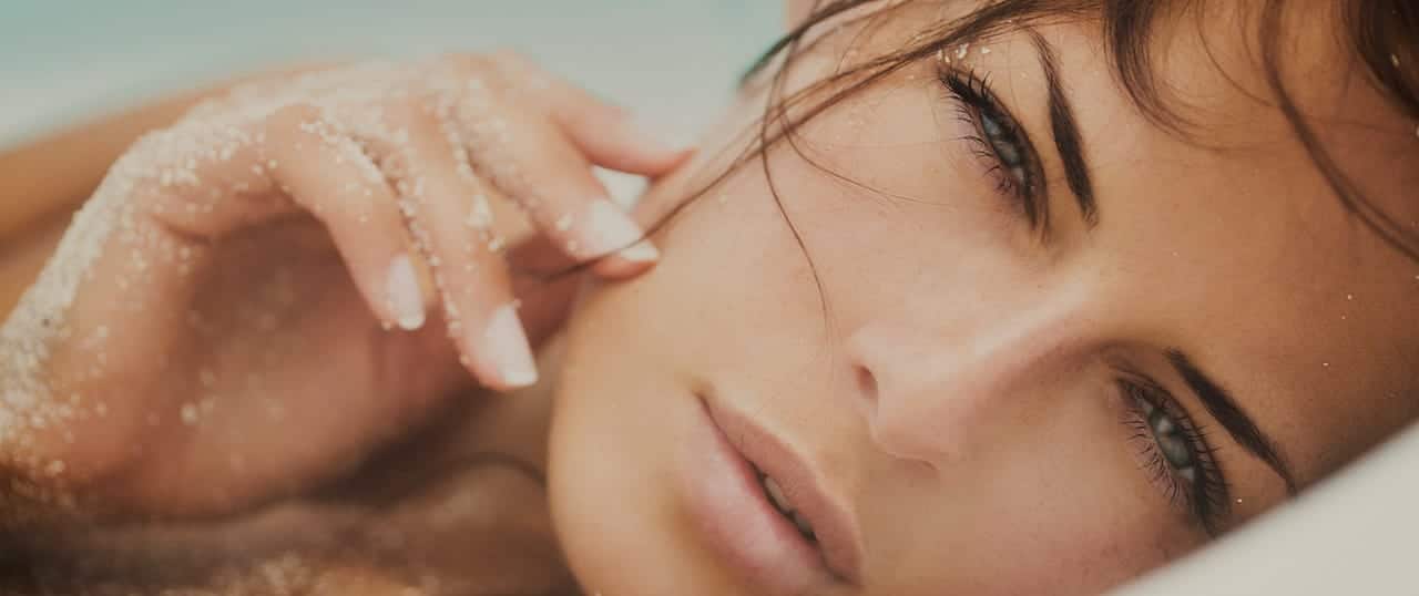 headshot of woman with hands on her face squinting