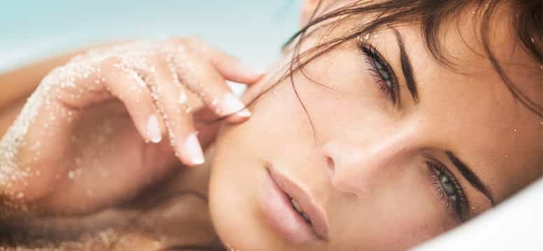 closeup portrait of a woman laying in the sand on the beach