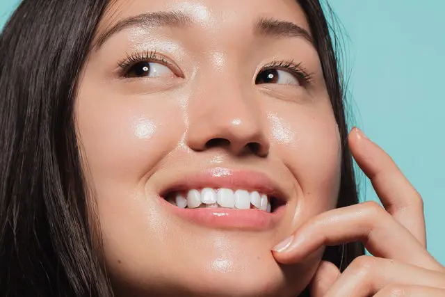 happy asian female smiling against a bright teal blue background