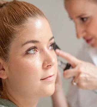 woman being examined on the side of her head by doctor