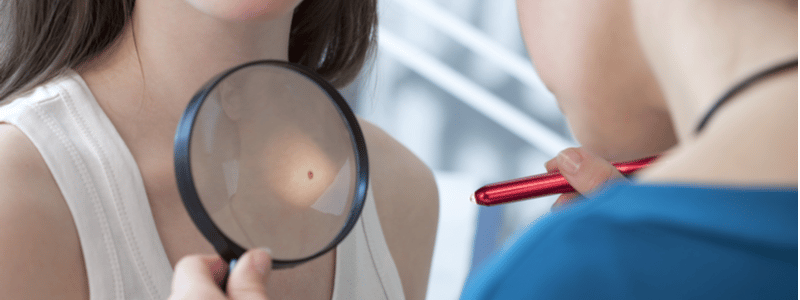 Oncologist examining female patient with magnifier in clinic