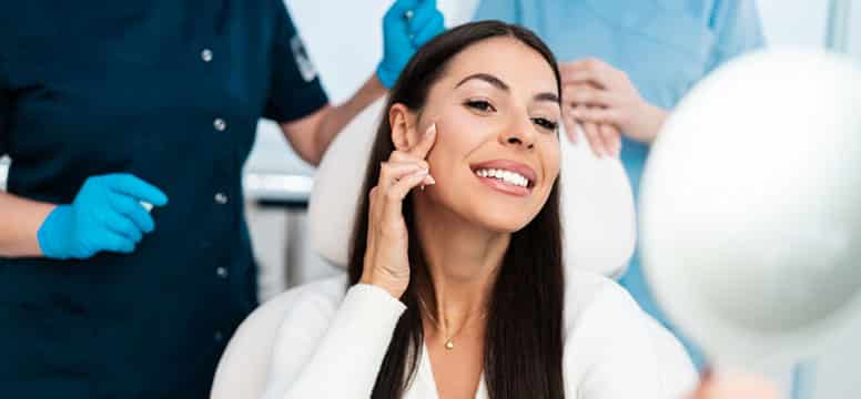 Bellafill boca raton fl - brunette woman looking at her face a dermatologists office