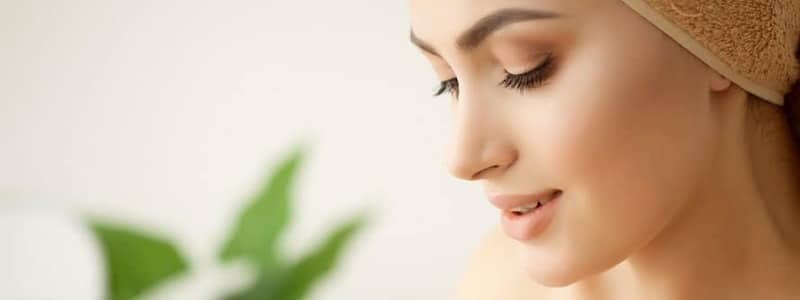 Studio shot of beautiful young woman applying moisturizer cream onto her face (1)