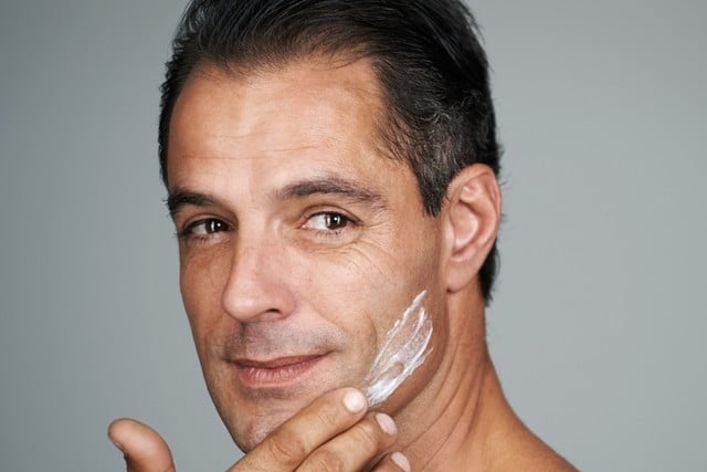 Studio portrait of a handsome mature man applying moisturizer to his skin.